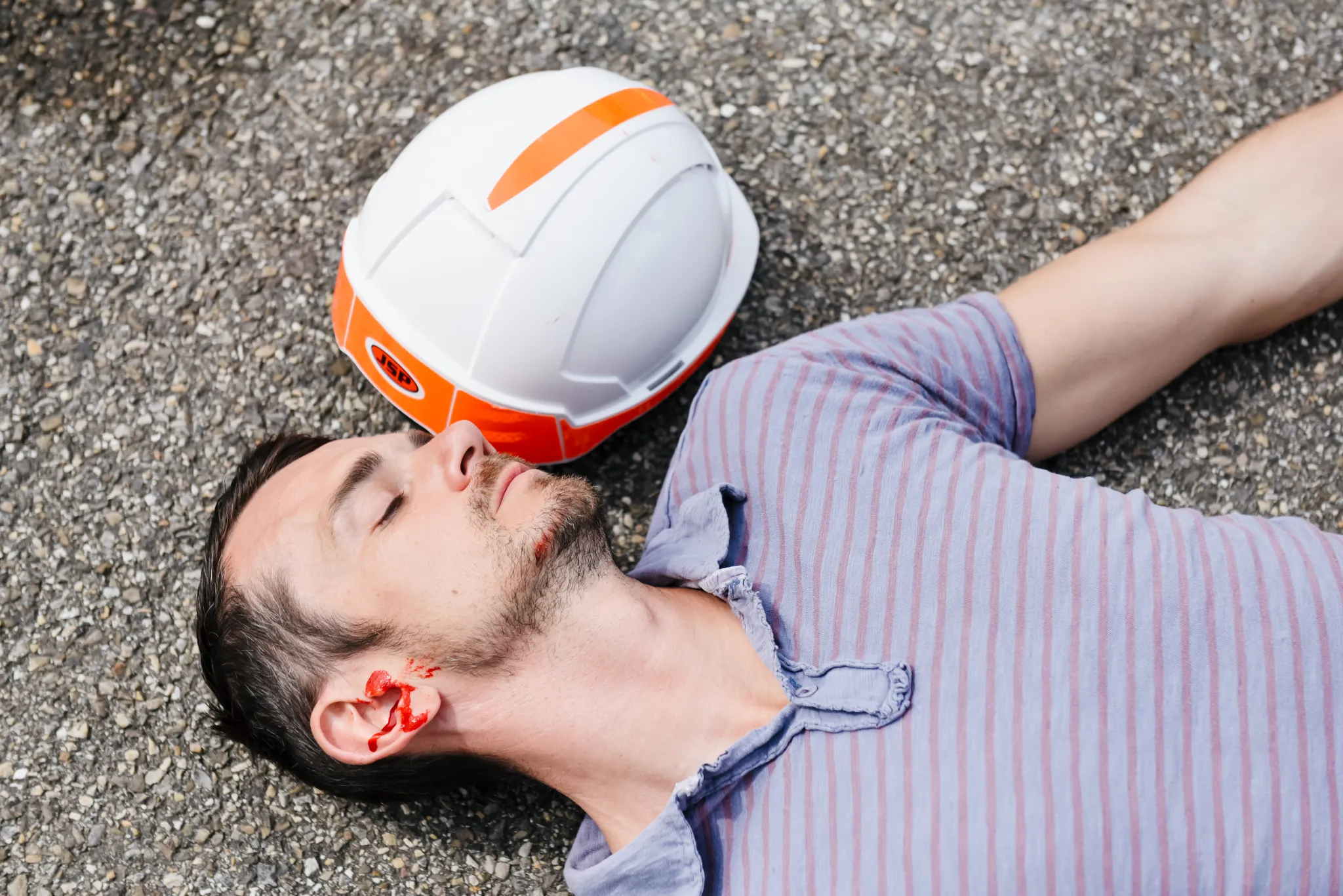 Homme allongé avec un casque de sécurité à côté.